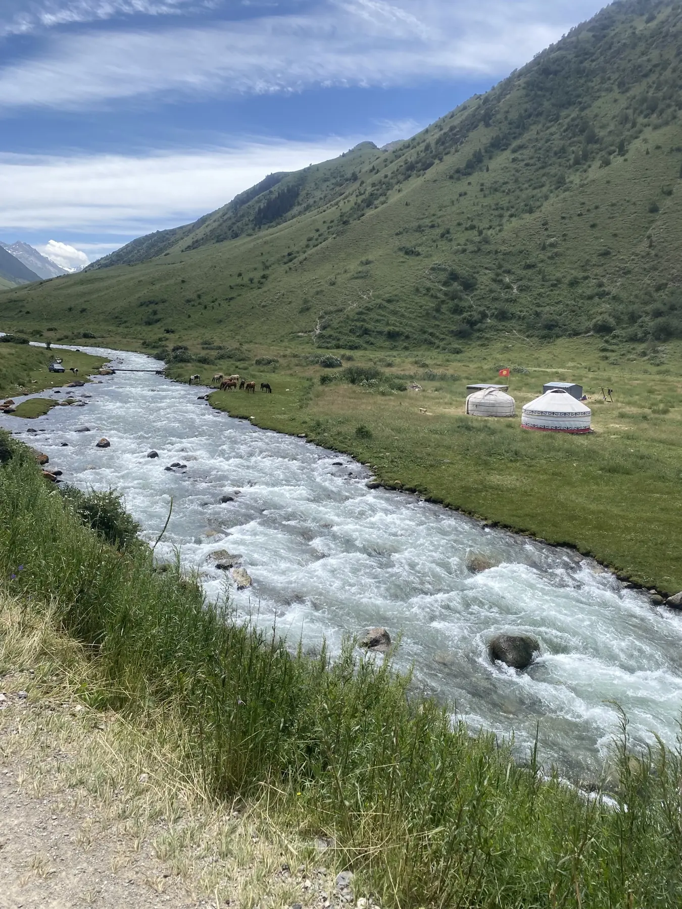 Rivière dans la vallée verte de Besh-Tash, yourtes et chevaux sur la rive