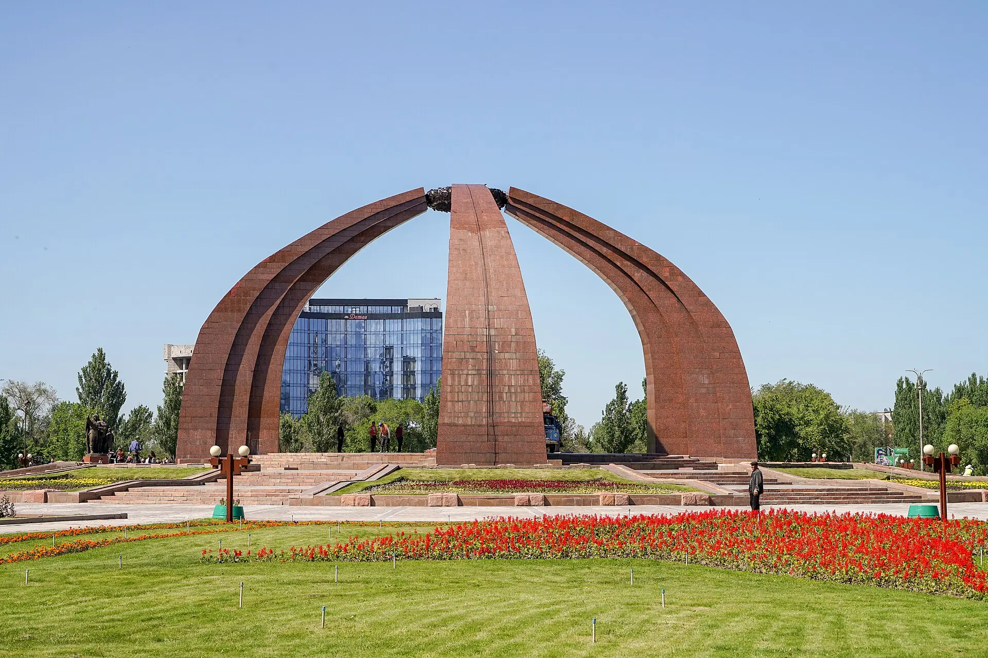 Мемориал на площади Победы: три каменные арки в форме каркаса юрты, клумбы и газон перед ними